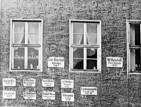 Hausfassade mit zwölf Gedenktafeln zwischen den Fenstern